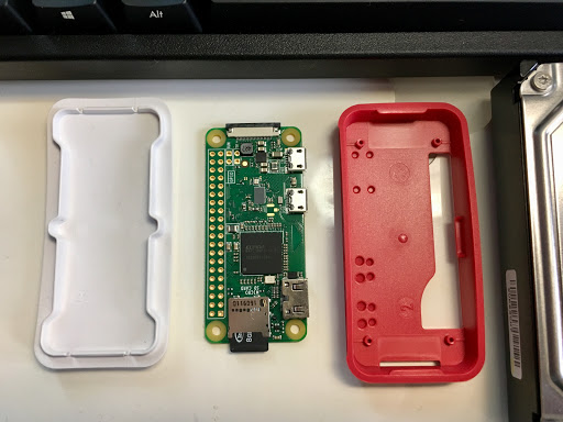 分解したRaspberry Pi Zero本体と赤白のケースを並べた様子